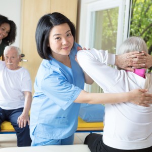 Woman chiropractic assistant helping a patient with chiropractic back exercises