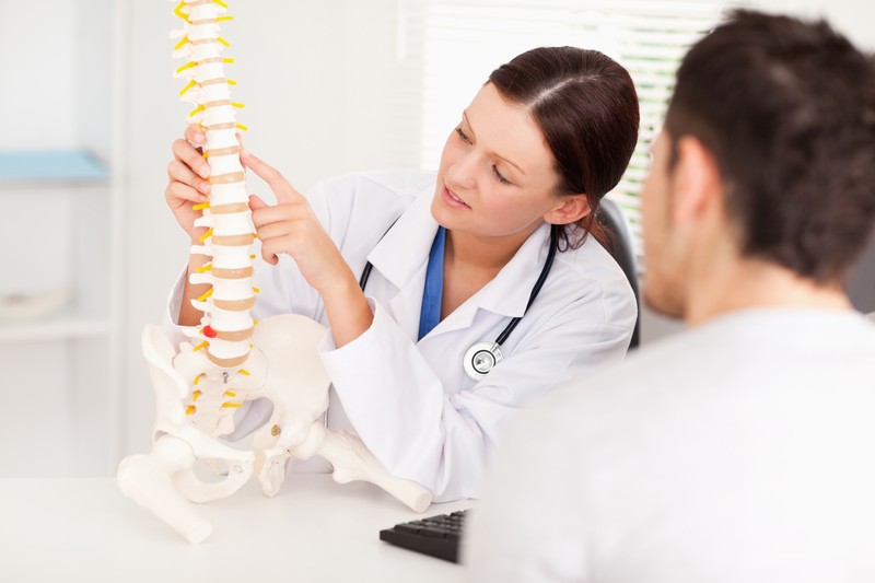 Doctor showing a patient a model of their spine to explain spine health