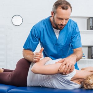 Chiropractor adjusting a woman's back on a table.