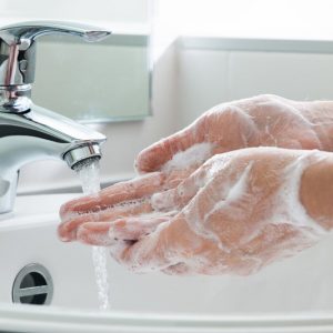 Upclose image of a person washing their hands in a sink with soap.