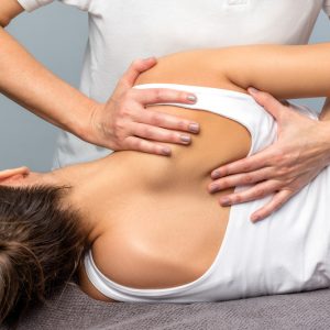 Young woman having her back adjusted by a female chiropractor.