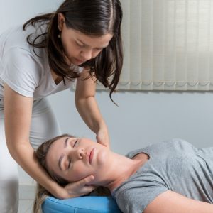 Woman laying on medical bed while female chiropractor performs a chiropractic manipulation on her neck.