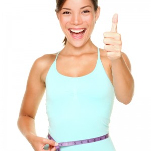 weight loss woman smiling happy excited standing with measuring tape giving thumbs up success hand sign isolated on white background. Asian female fitness model.