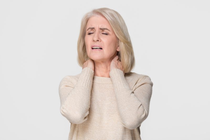 Older woman holding neck in pain.